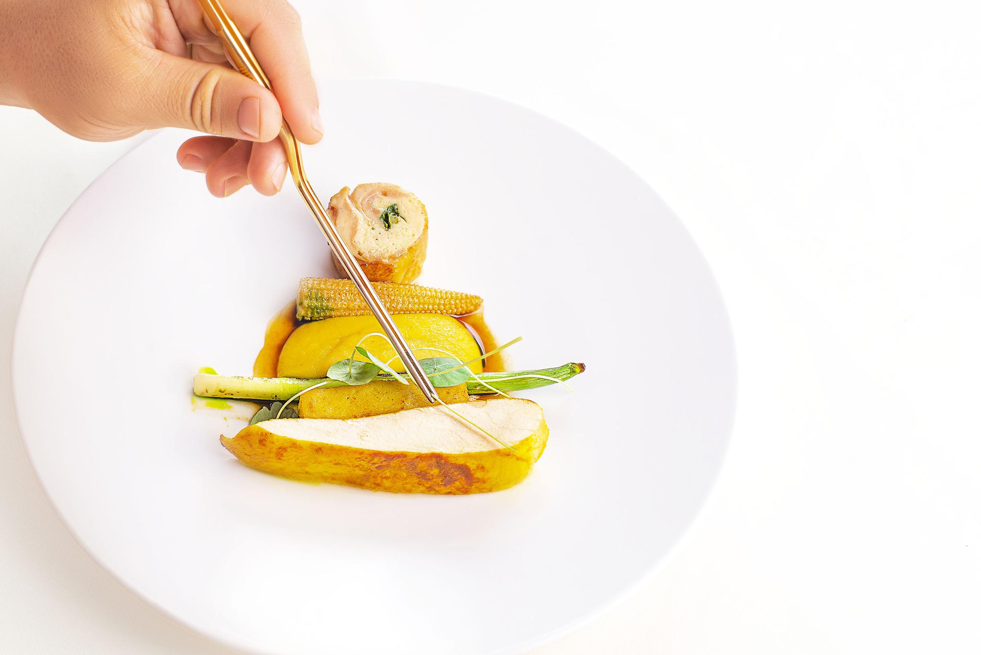 Chef plating a seasonal dish in a bright studio